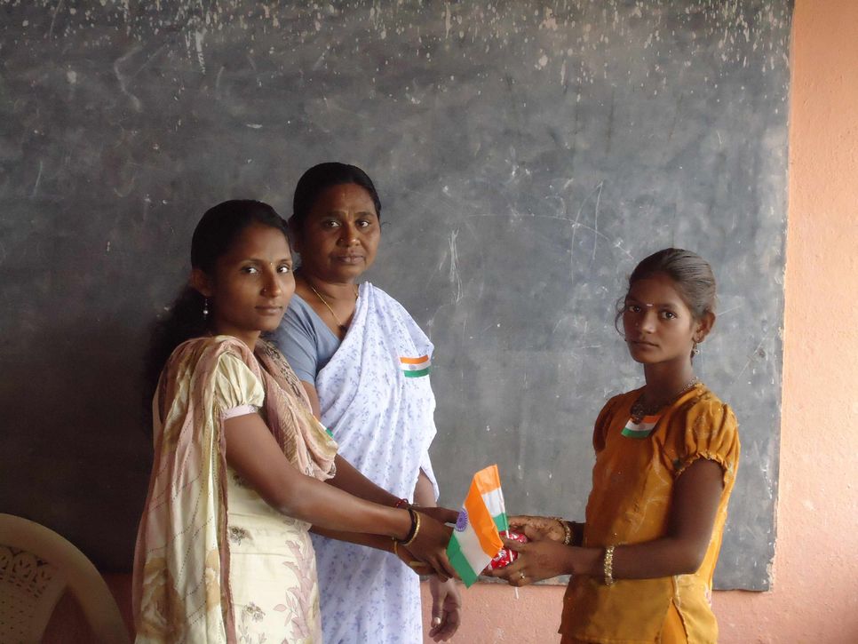 Lehrerinnen überreichen in einer Schule in Indien einem Mädchen das Zeugnis.