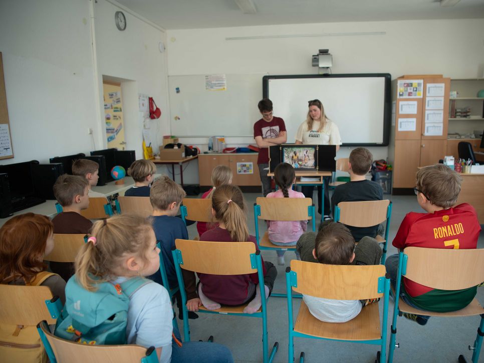 Kindergruppe sitzt vor Kamishibai Erzähltheater